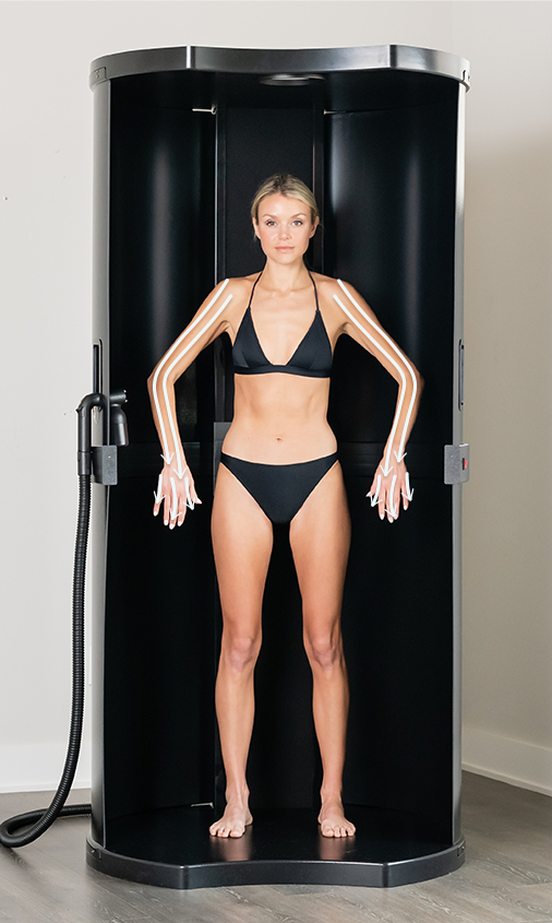 model standing in spray tan booth